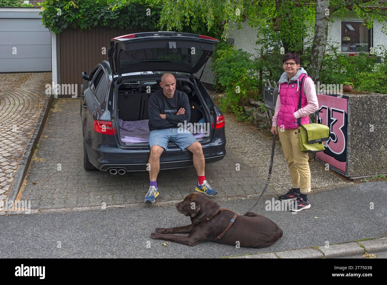 Couple with dog in front of departure by car, Bavaria, Germany Stock Photo
