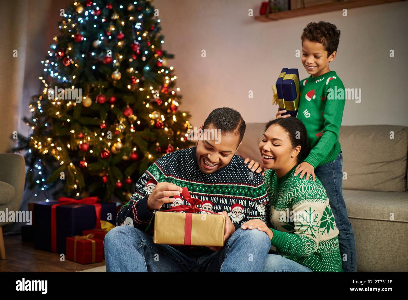 happy african american man unpacking present while his wife and son ...