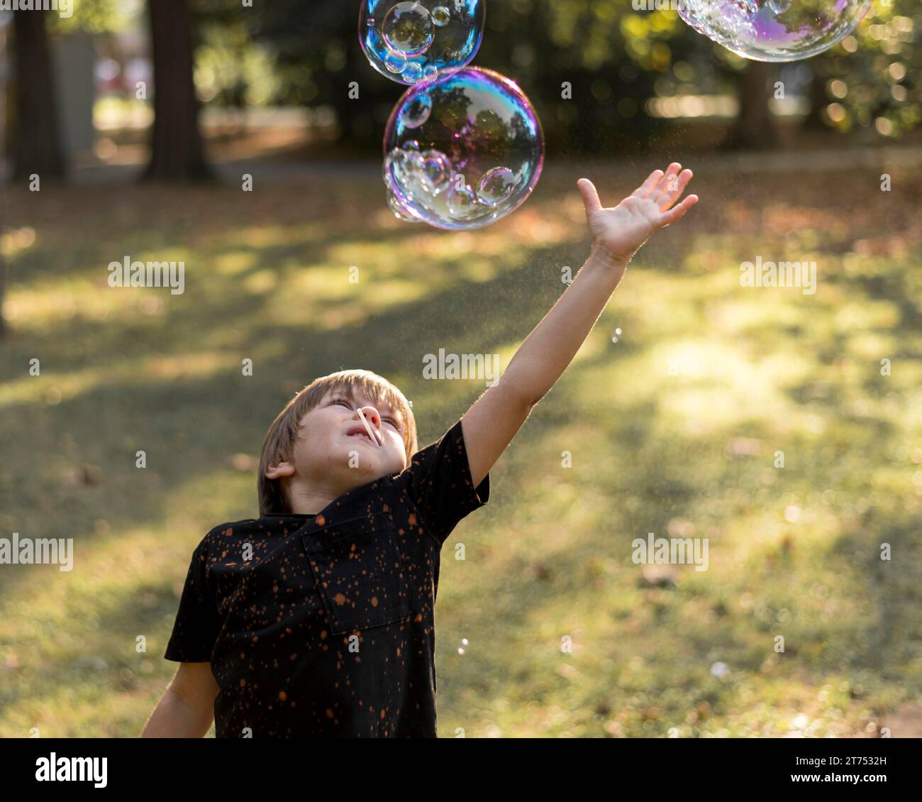 Kid trying catch soap bubbles Stock Photo