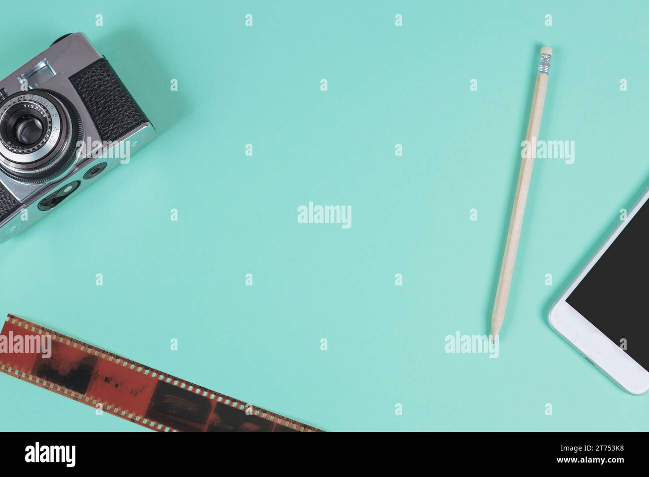 Pencil mobile phone camera old film strip against turquoise background