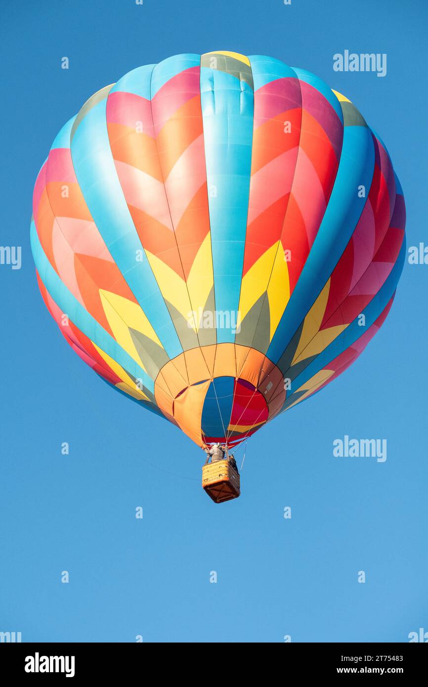 A brightly colored hot air balloon with a geometric pattern flying in a ...