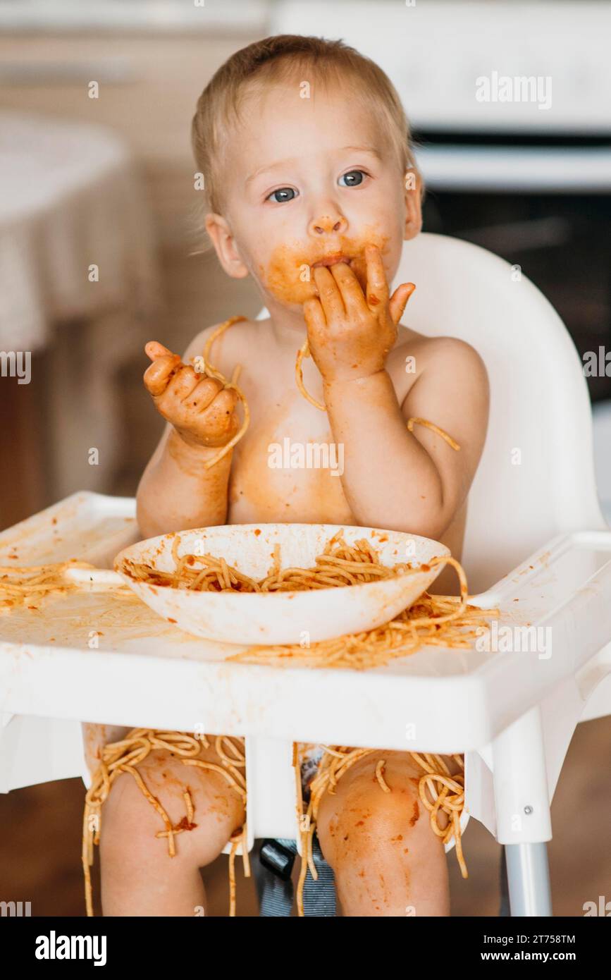 Baby boy licking his fingers after eating pasta Stock Photo Alamy