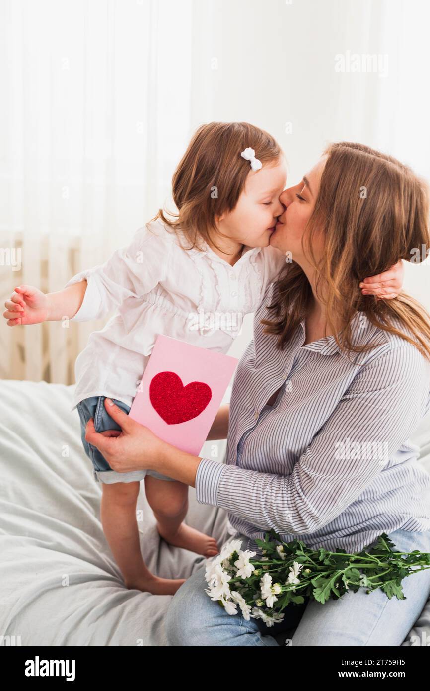 Daughter mother with greeting card kissing Stock Photo
