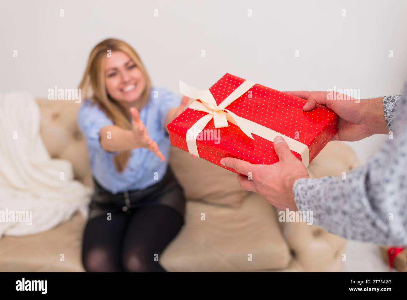 Guy giving present young smiling lady settee Stock Photo