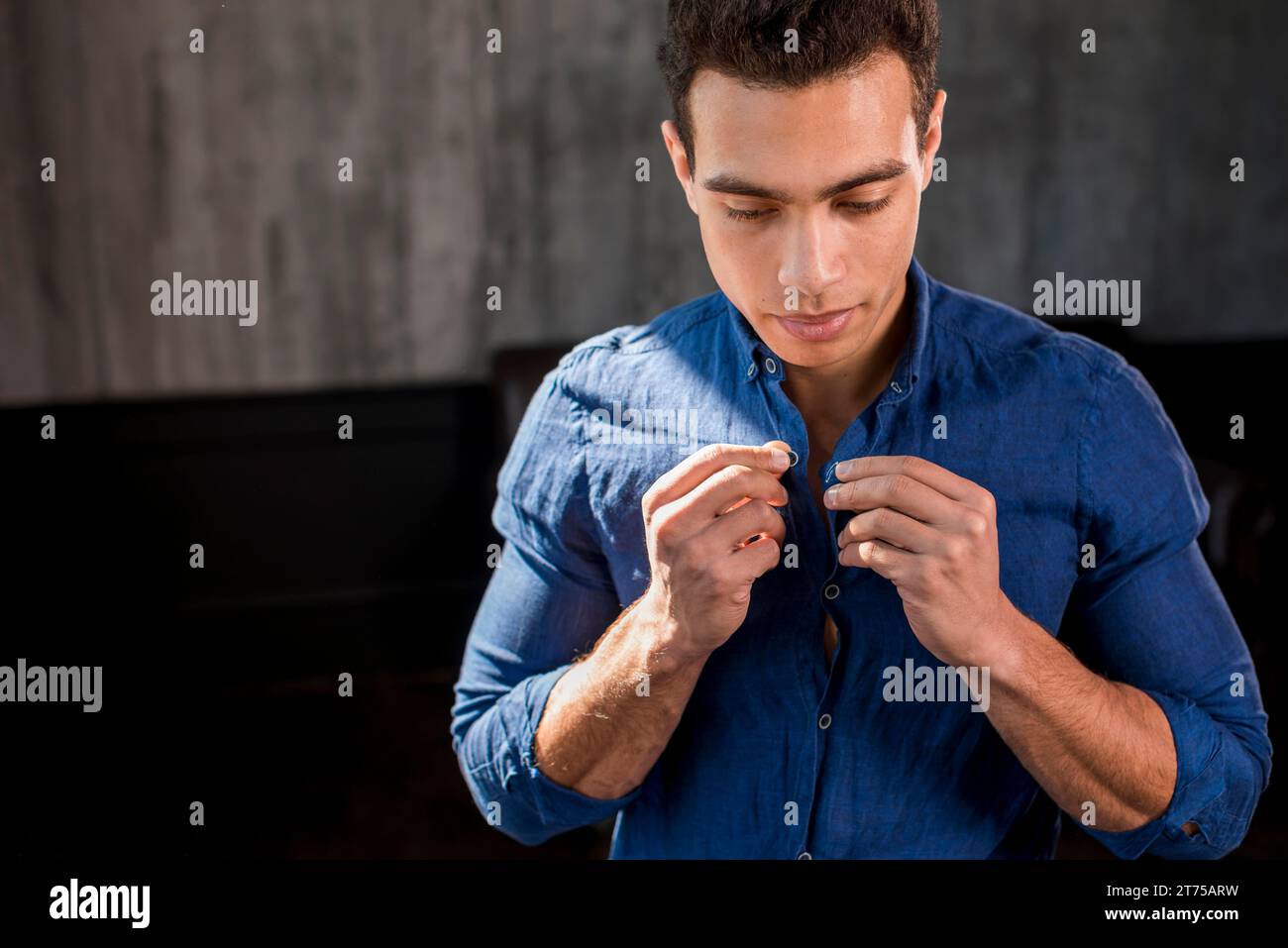 Portrait man buttoning his blue shirt Stock Photo