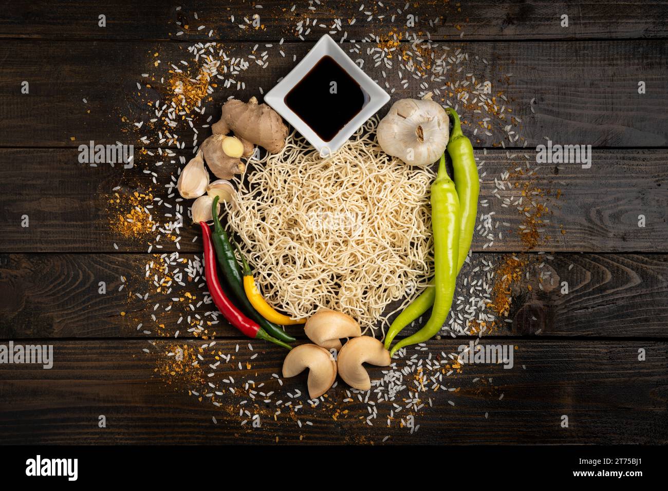 Chinese food ingredients, noodles, hot peppers, fresh ginger, soy sauce, garlic, rice, spices, and fortune cookies on a wooden background Stock Photo