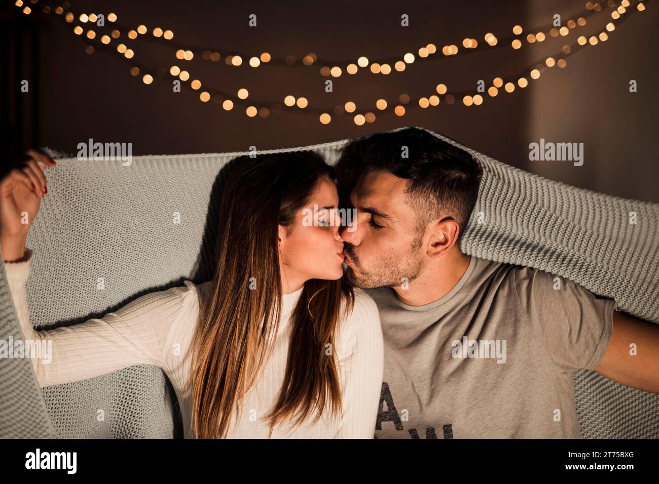 Young woman kissing with man coverlet Stock Photo