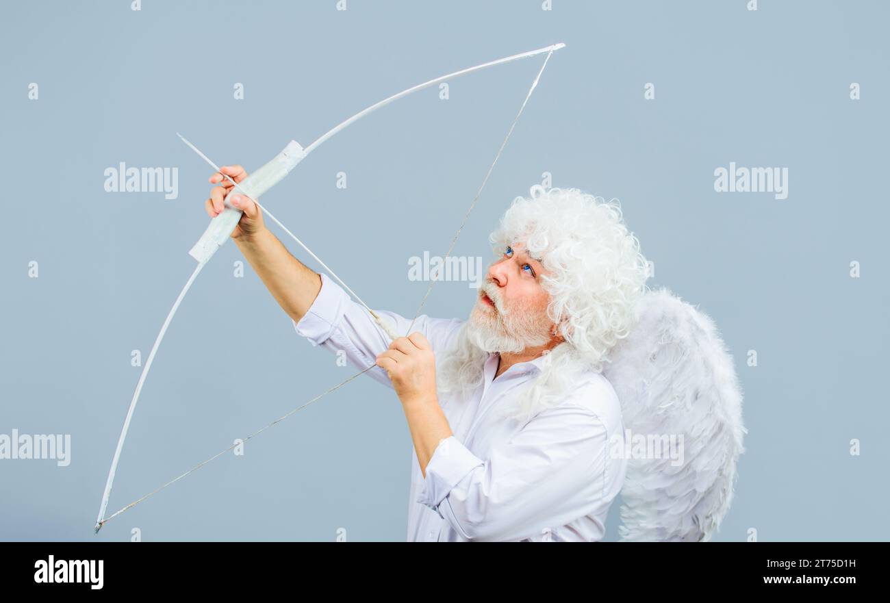Happy Valentines Day. Bearded man in white curly wig and angel wings shooting love arrow. Valentines day cupid angel with bow and arrow. Arrow of love Stock Photo