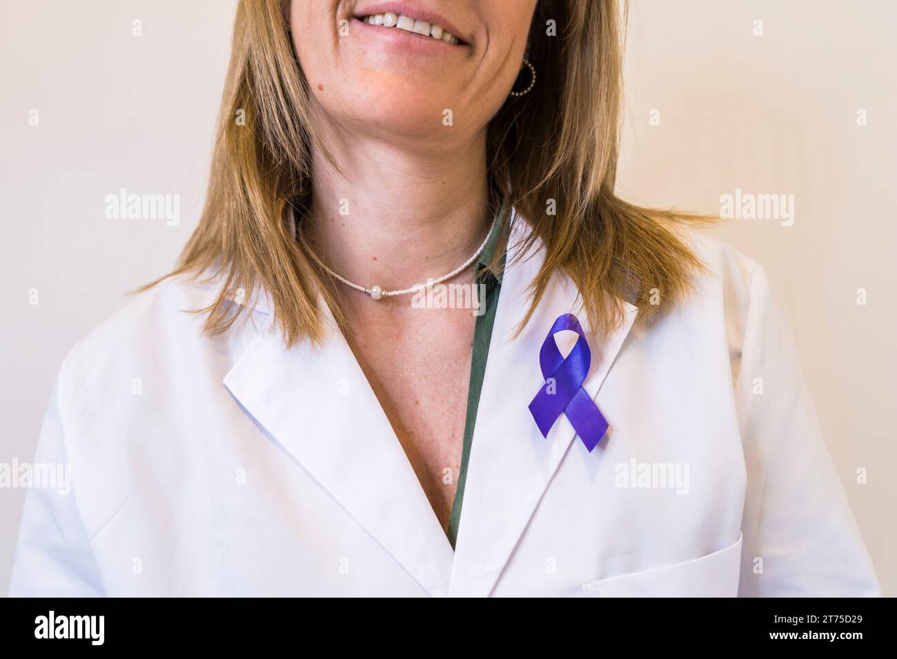 Close-up of purple ribbon pinned on white lab coat of female doctor. Stock Photo