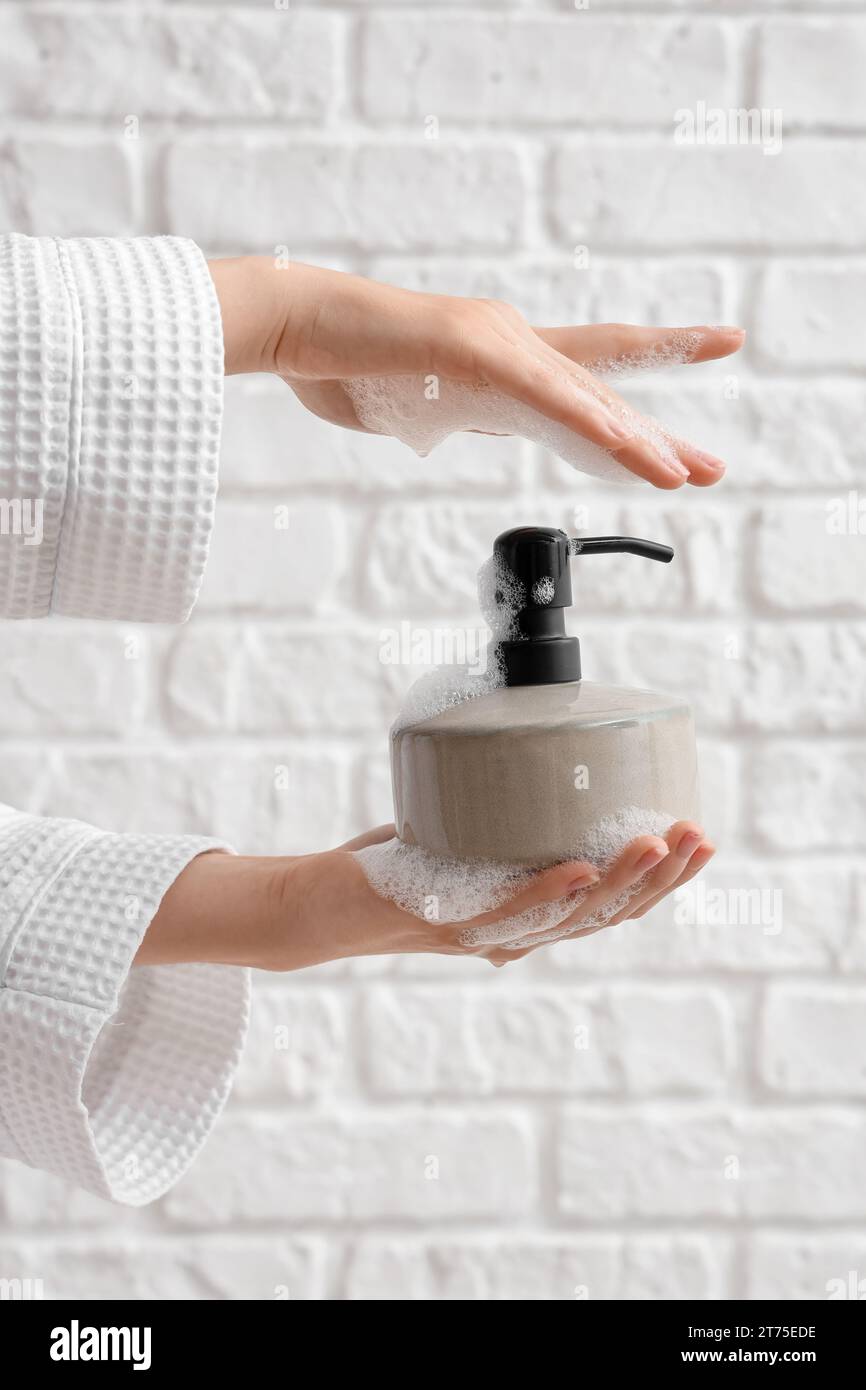 Hands with liquid soap on white brick background Stock Photo