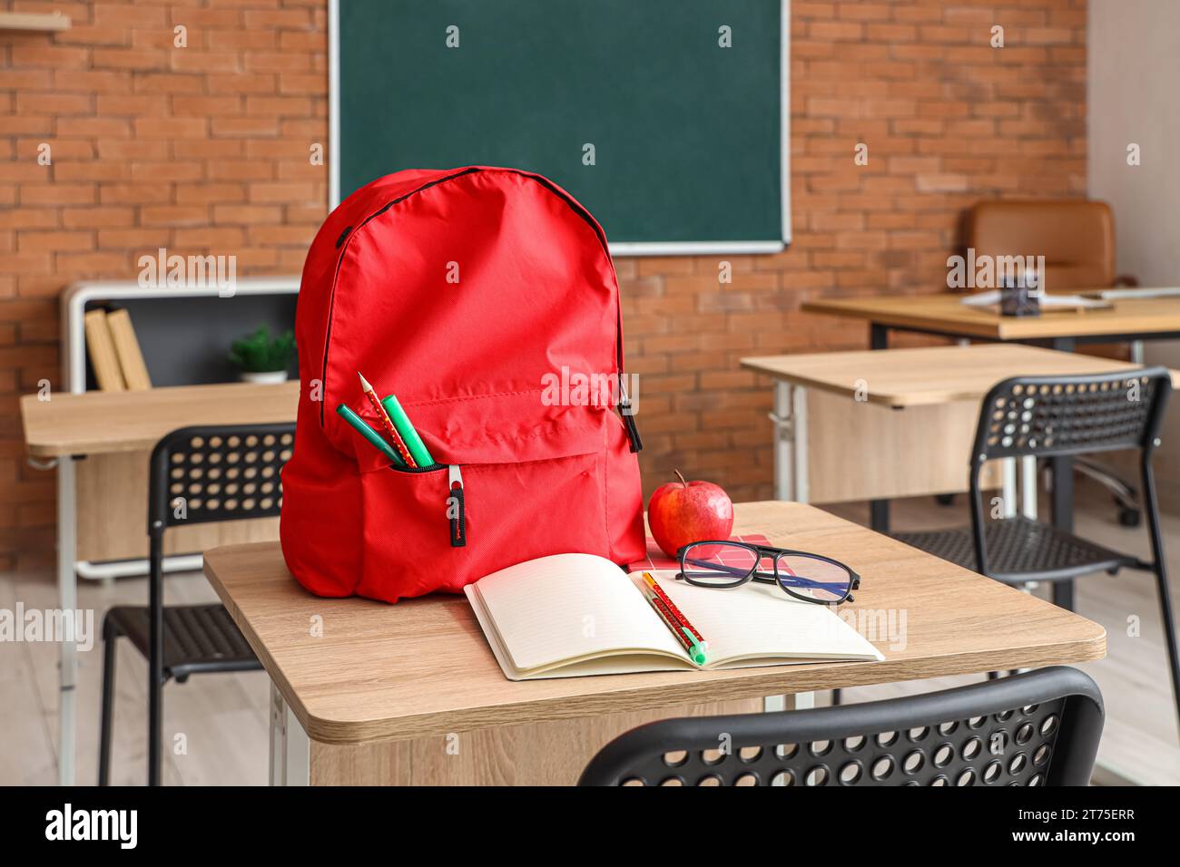 Red school backpack with stationery on desk in classroom Stock Photo ...