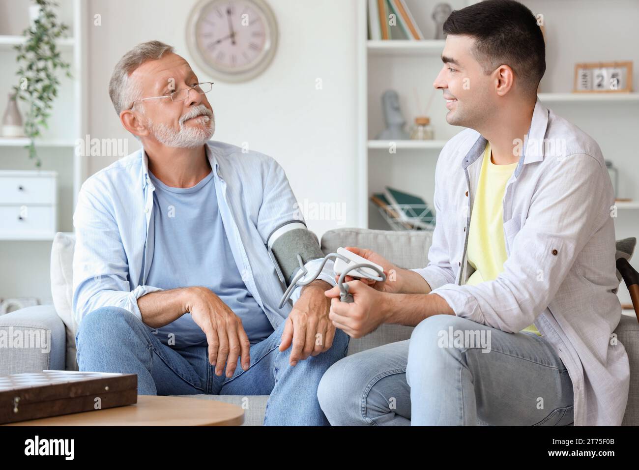 Young man measuring blood pressure of his father at home Stock Photo ...