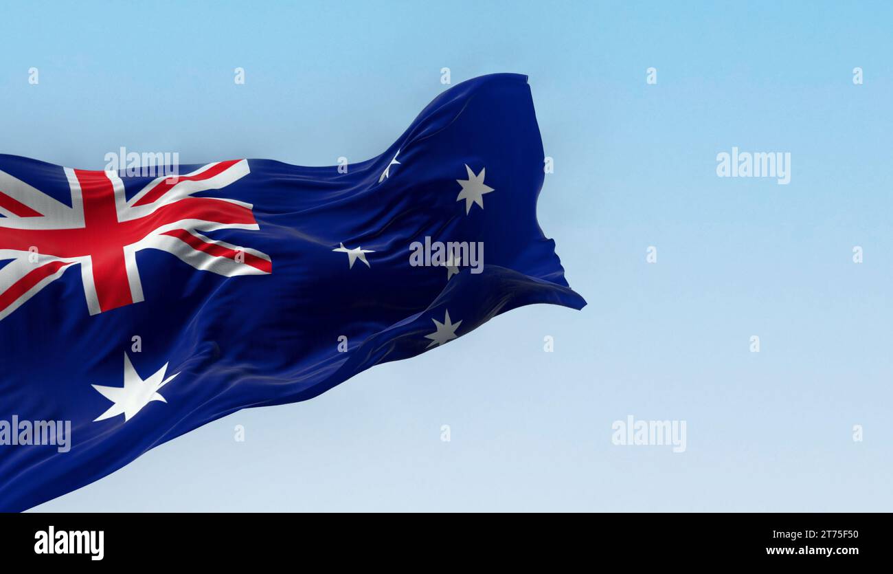 Flag of Australia, vividly colored, dynamically waving against a soft-focus cloudy sky backdrop Stock Photo