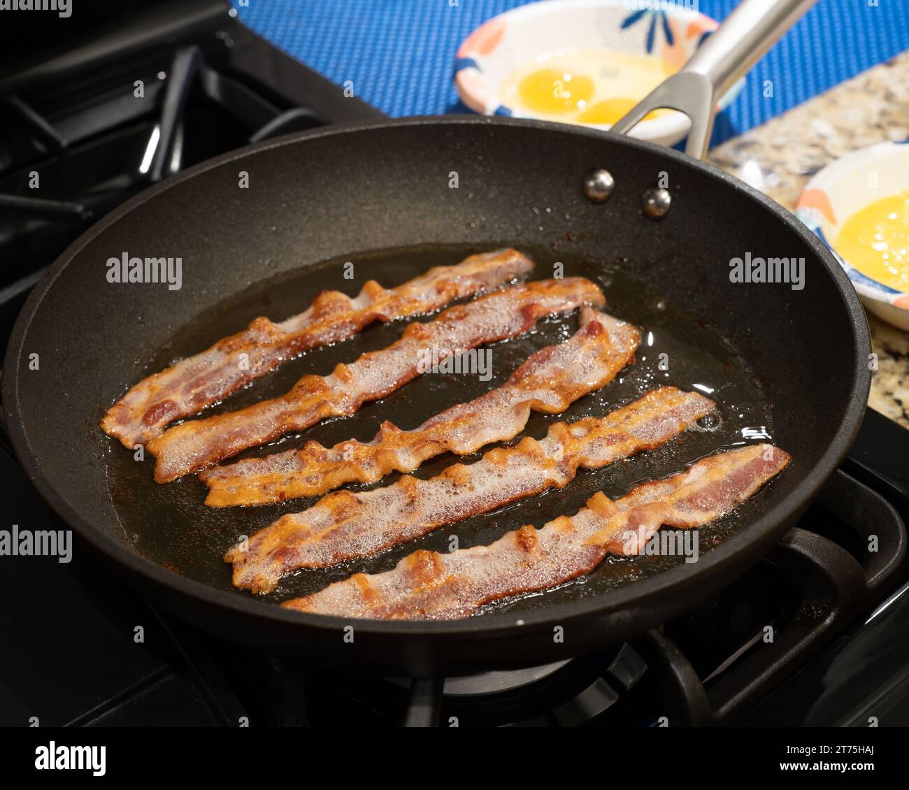 Bacon frying  or cooking in a skillet for breakfast in a home kitchen in the USA. Stock Photo