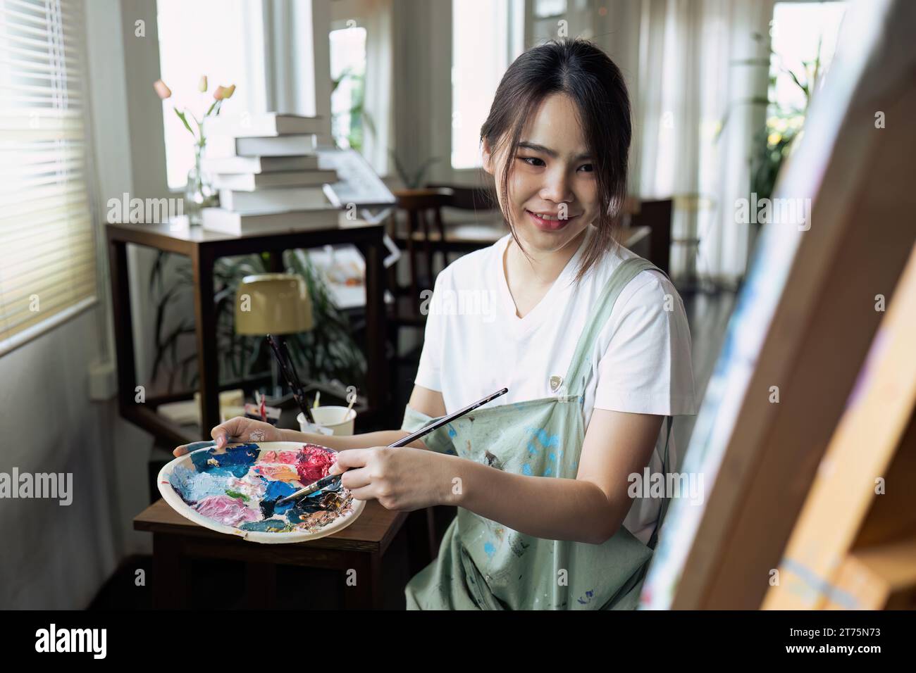 Female artist hold color palette and paintbrush for painting during ...