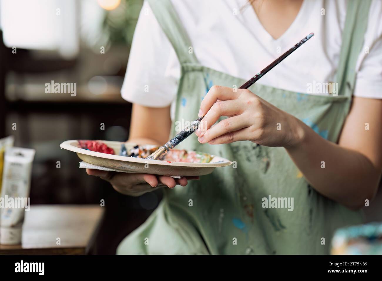 Female artist hold color palette and paintbrush for painting during ...