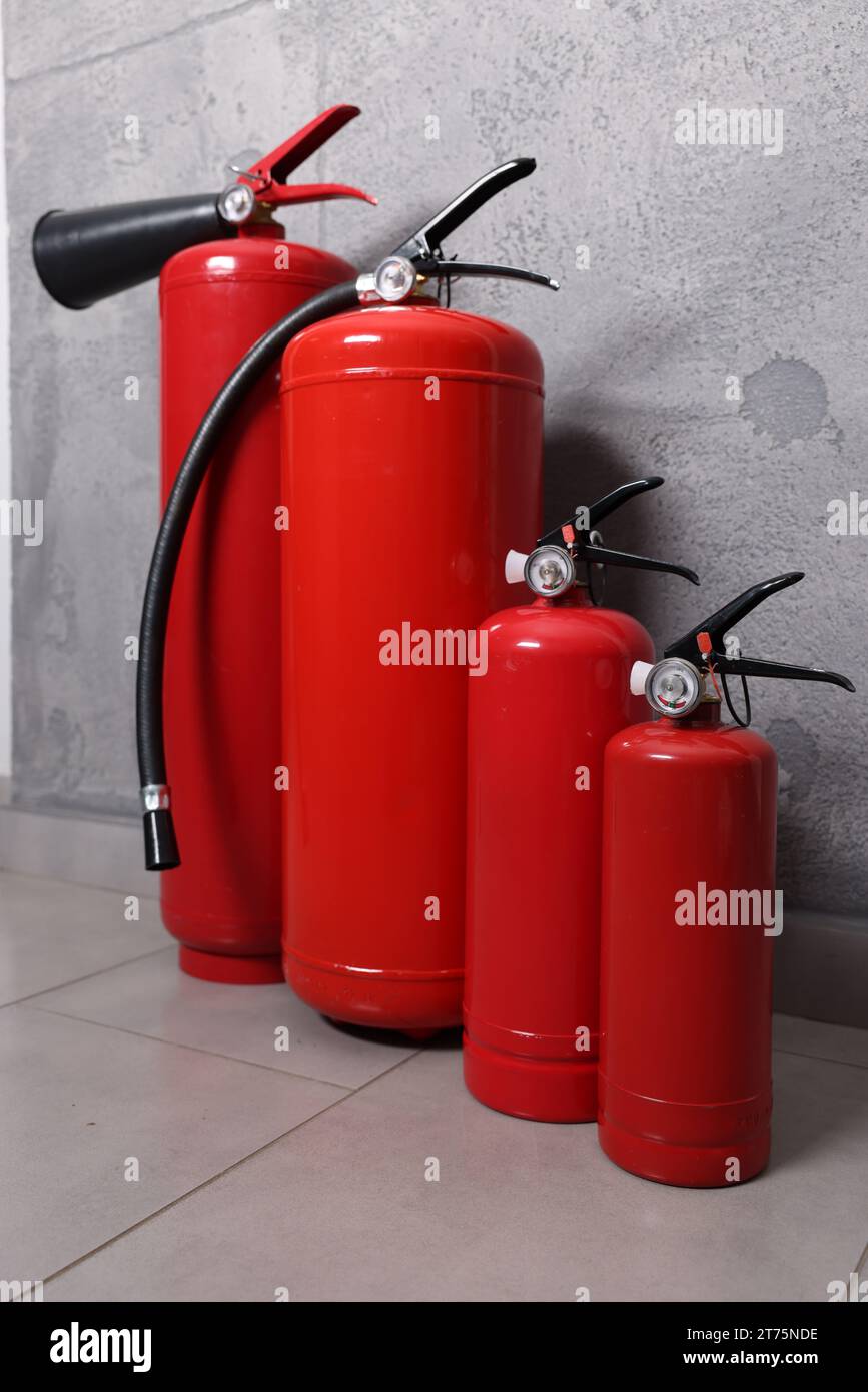 Four red fire extinguishers near grey wall Stock Photo Alamy