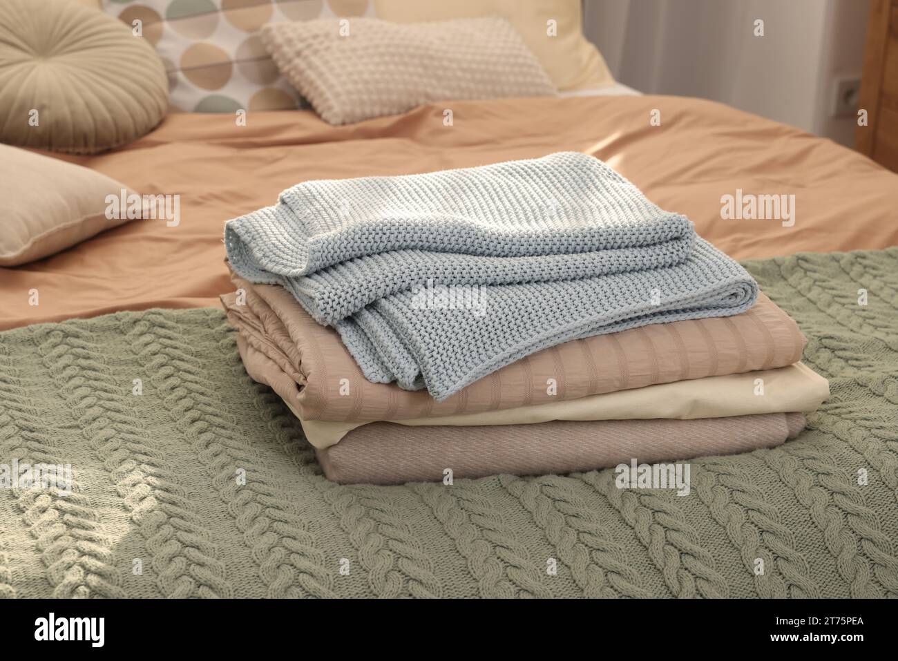 Stack of different folded blankets on bed indoors. Home textile Stock Photo
