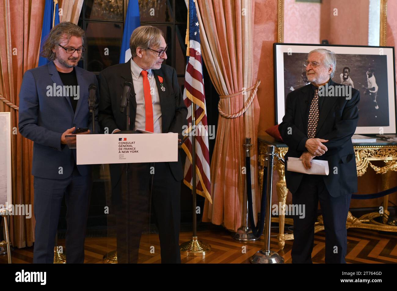 New York, USA. 13th Nov, 2023. French Photojournalist Jean-Francois Leroy (2nd left) speaks before gathered guest before presenting photojournalist Jean-Pierre Laffont (r) with the insignia of Knight in the National Order of the French Legion of Honor, at the Consulat General de France in New York, NY, November 13, 2023. (Photo by Anthony Behar/Sipa USA) Credit: Sipa USA/Alamy Live News Stock Photo