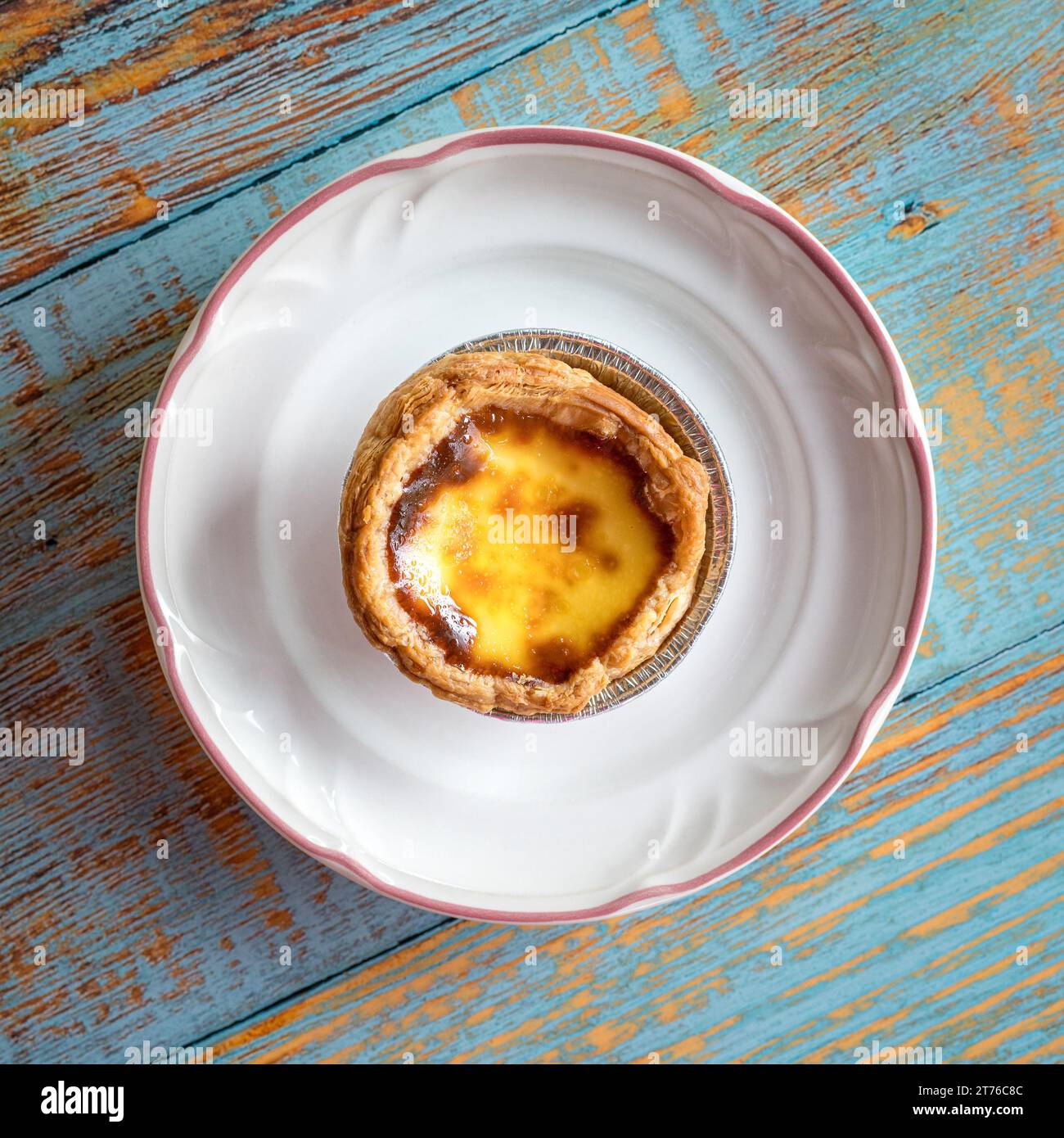 Portuguese egg tart on a white plate. Top view. Stock Photo