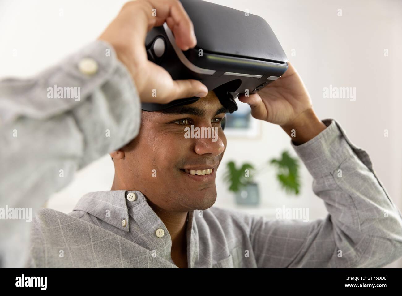 Happy biracial man using vr headset at home Stock Photo