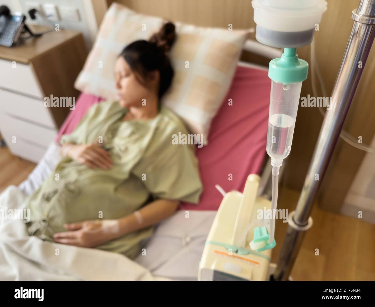 medical saline IV drip with pregnant woman resting on a bed in hospital Stock Photo