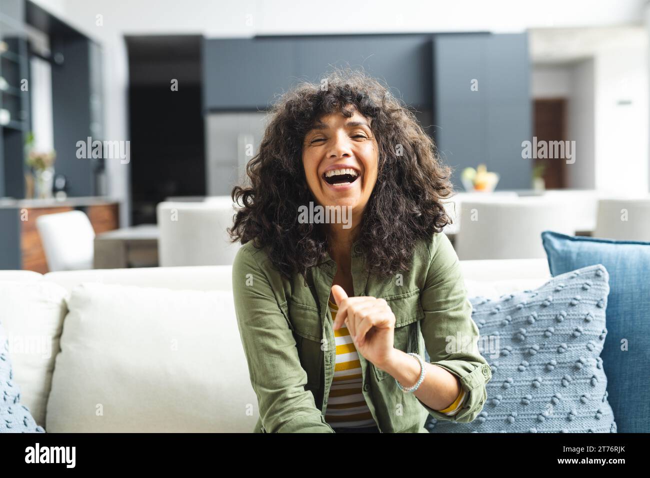 Happy mature caucasian woman having video call, laughing on couch in sunny living room, copy space Stock Photo