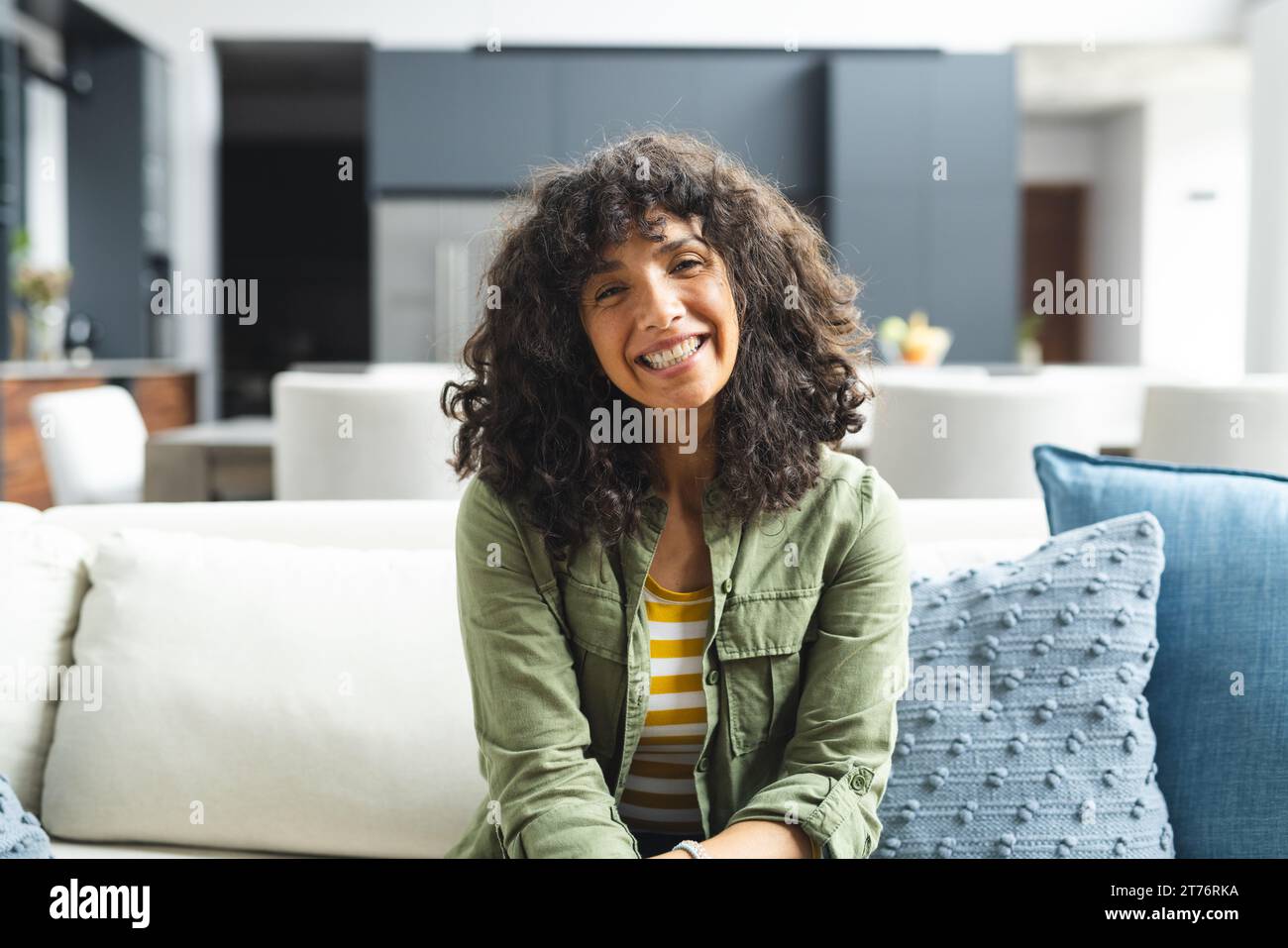 Happy mature caucasian woman having video call, smiling and listening on couch in sunny living room Stock Photo