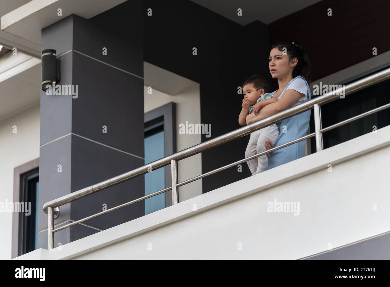stressed mother and infant baby at balcony of their house Stock Photo