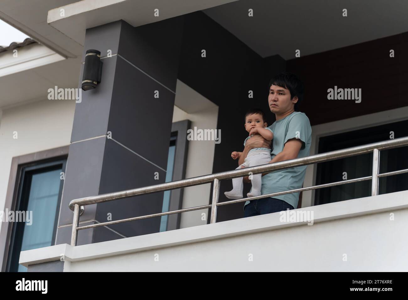 stressed father and infant baby at balcony of their house Stock Photo
