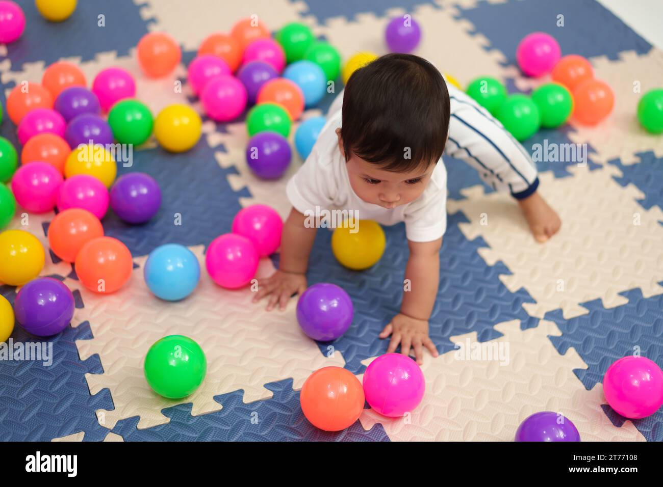 infant baby playing colorful plastic balls in playpen Stock Photo