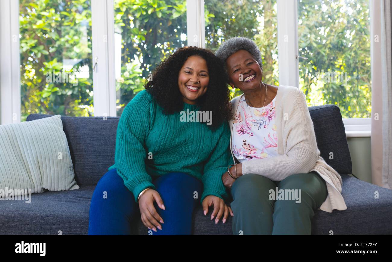 Senior happy african american mother and adult daughter embracing on couch at home, copy space Stock Photo