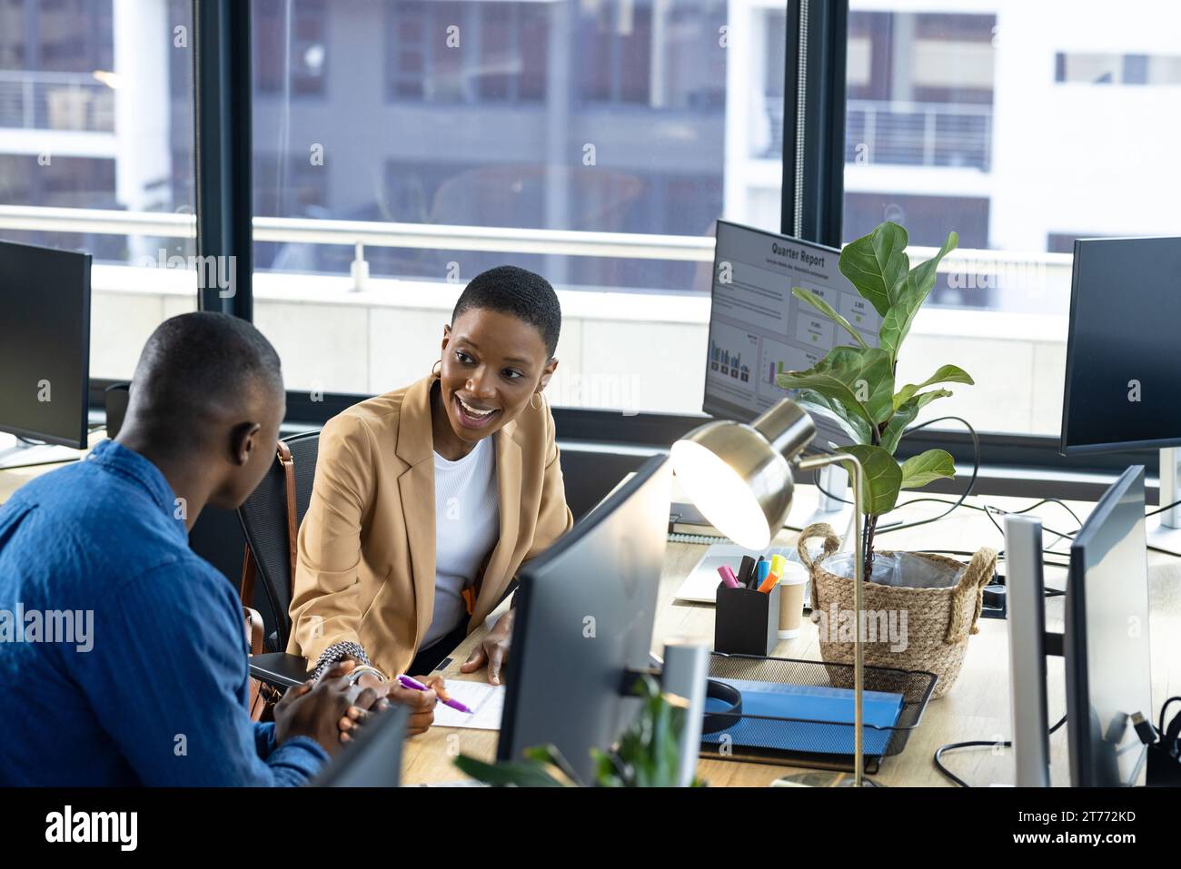Happy african american male and female colleague using computers at ...