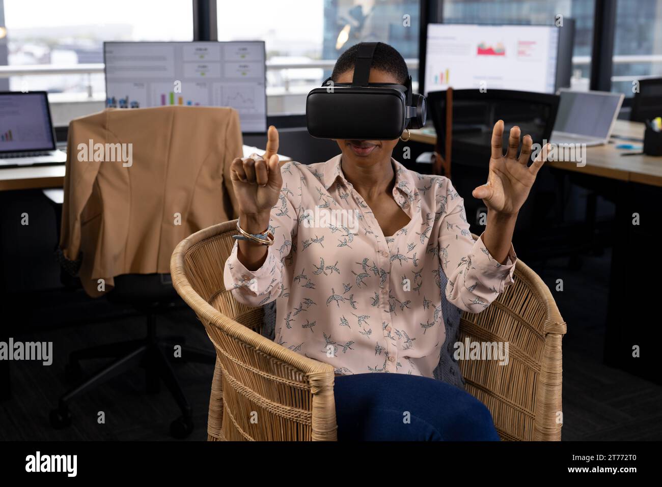 Happy african american casual businesswoman in vr headset using virtual interface in office Stock Photo