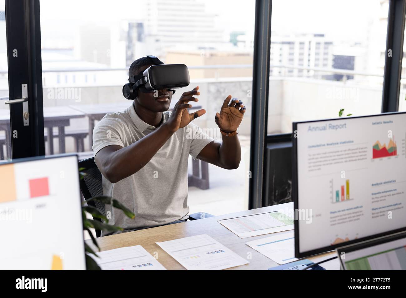 African american casual businessman wearing vr headset using virtual interface at office desk Stock Photo
