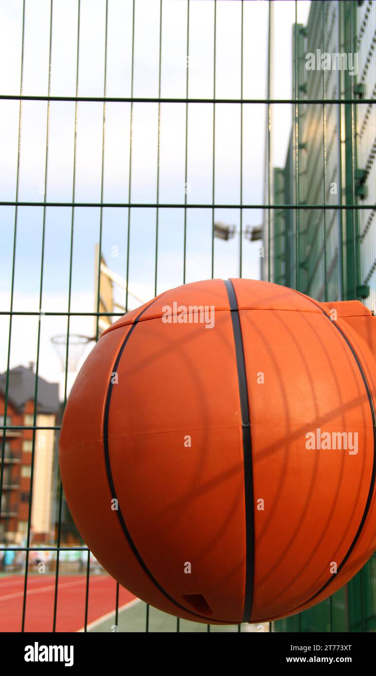 Plastic waste basket in the shape of a basketball ball on a metal grid