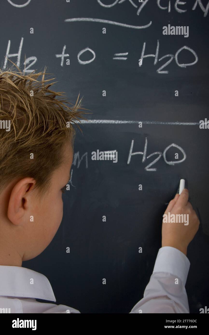 Back view of a school boy writing on a blackboard Stock Photo