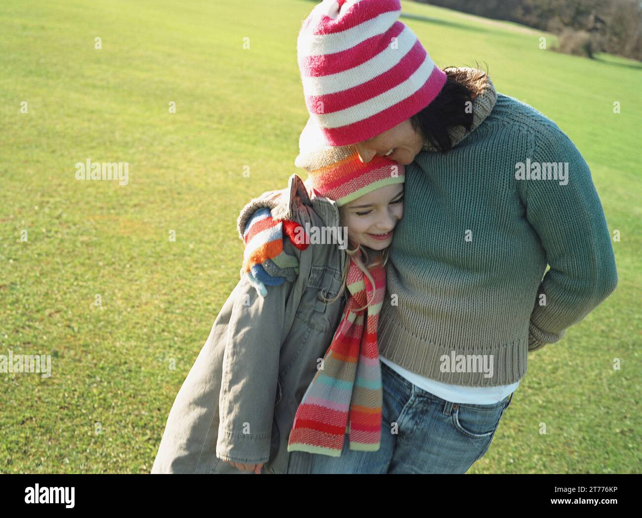 Woman and girl standing in a field hugging Stock Photo