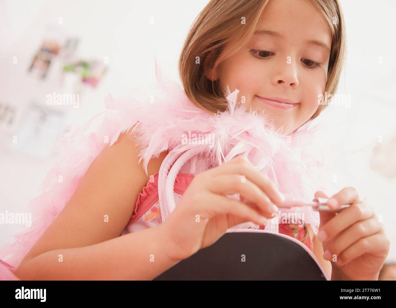 Girl wearing a pink feather boa holding a lip gloss Stock Photo