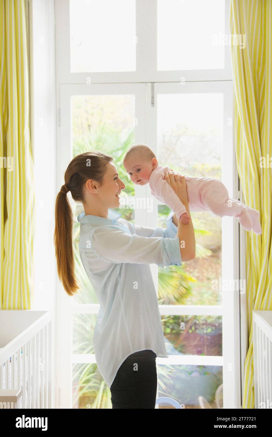 Mother Lifting Baby in Nursery Stock Photo Alamy