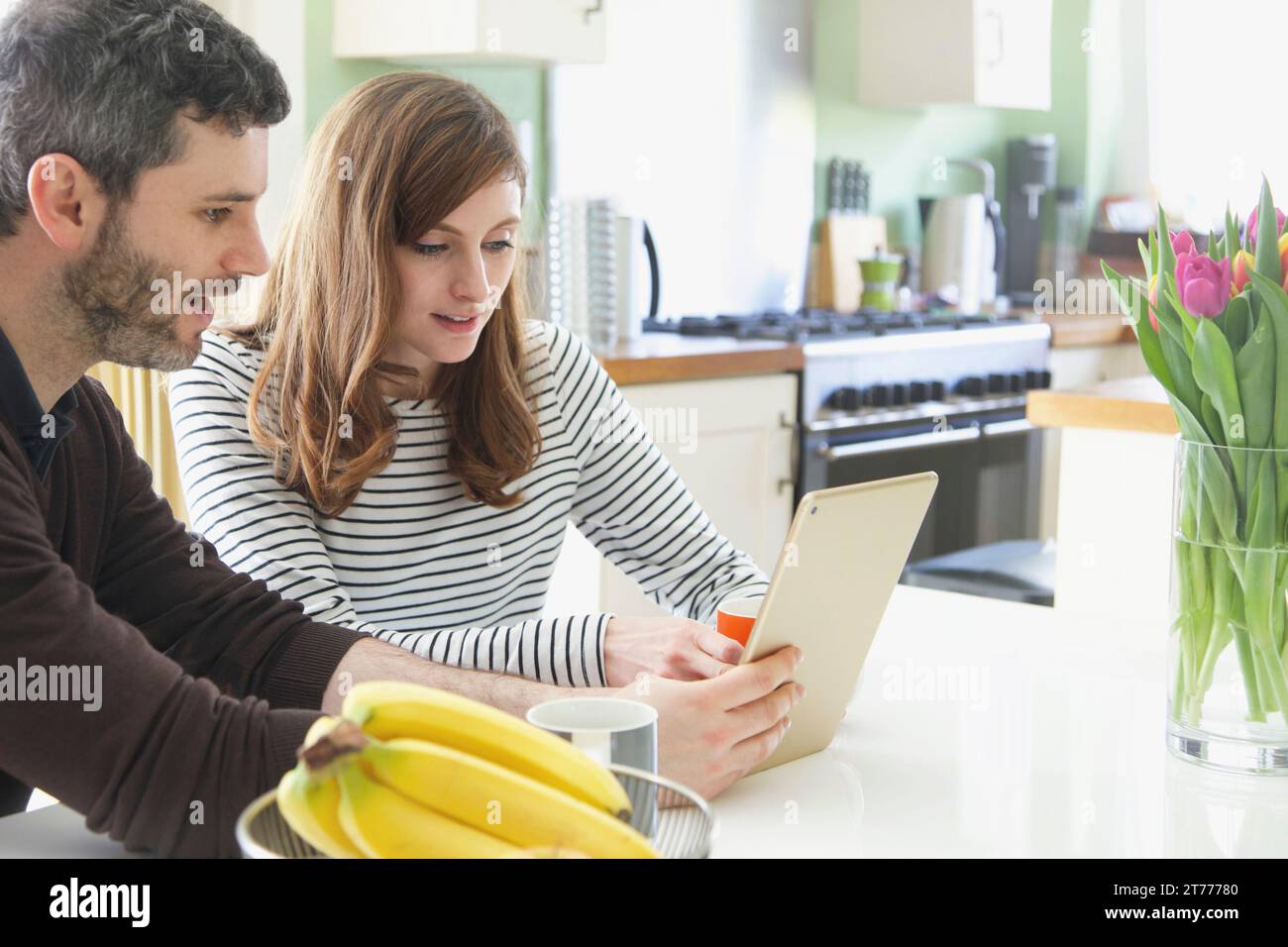 Couple Sitting at Table Using Digital Tablet Stock Photo