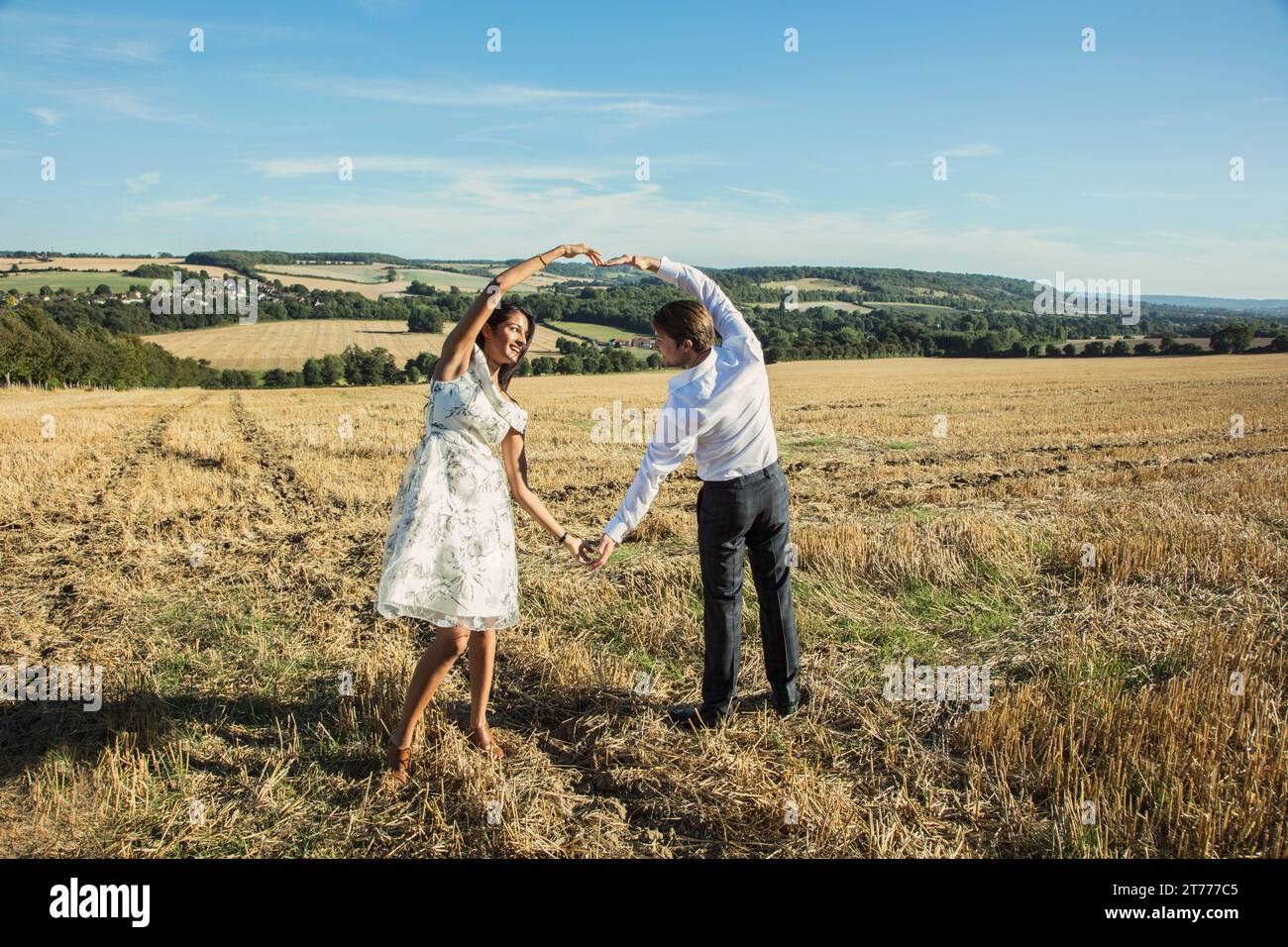 Couple in Field Holding Hands Making Heart Shape Stock Photo