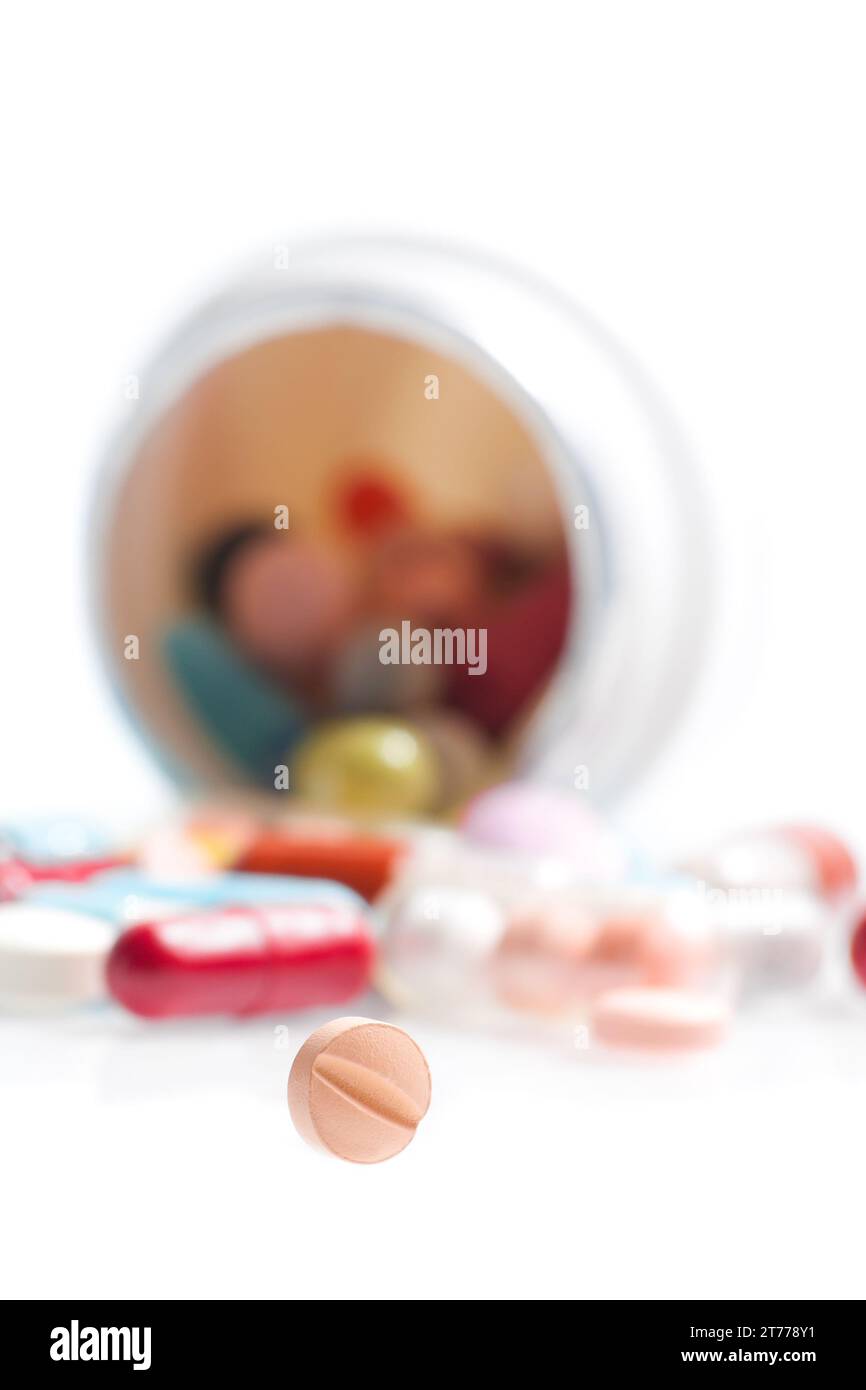 one small pill in laboratory in front of a colored pills on white table Stock Photo