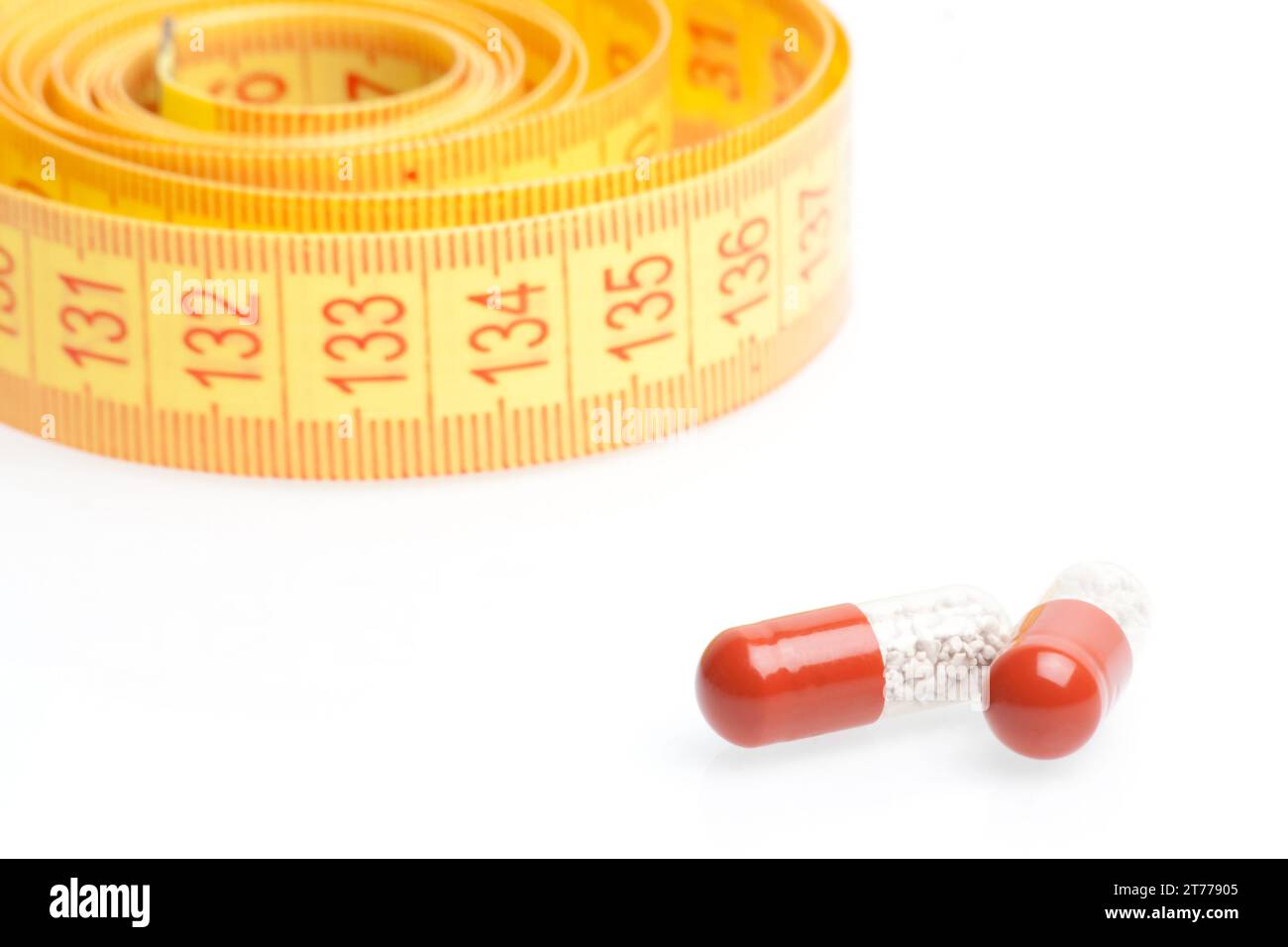 medical pills for dieting in front of measuring tape on a white background Stock Photo