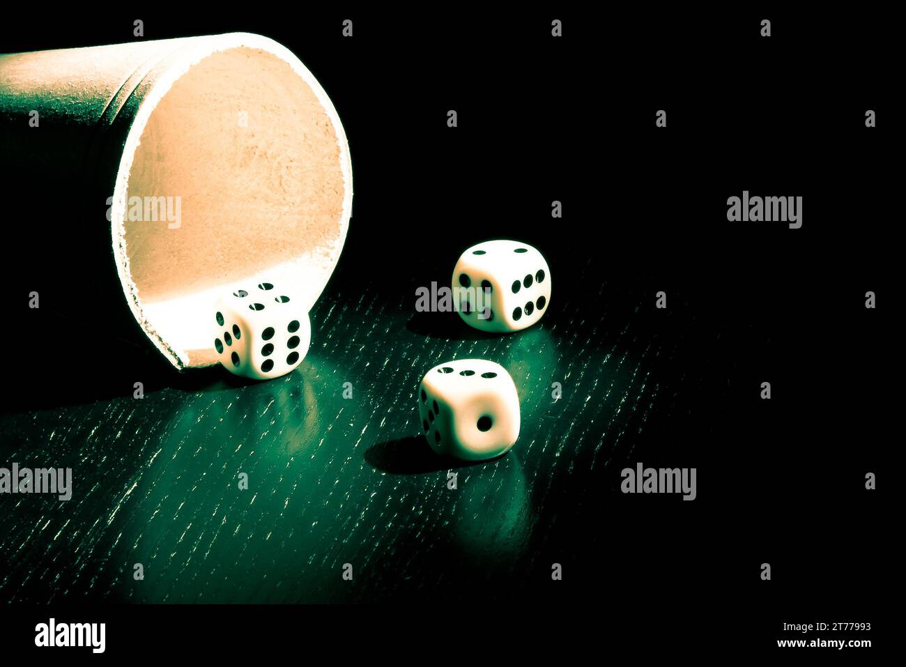 dice near a container under a green light Stock Photo