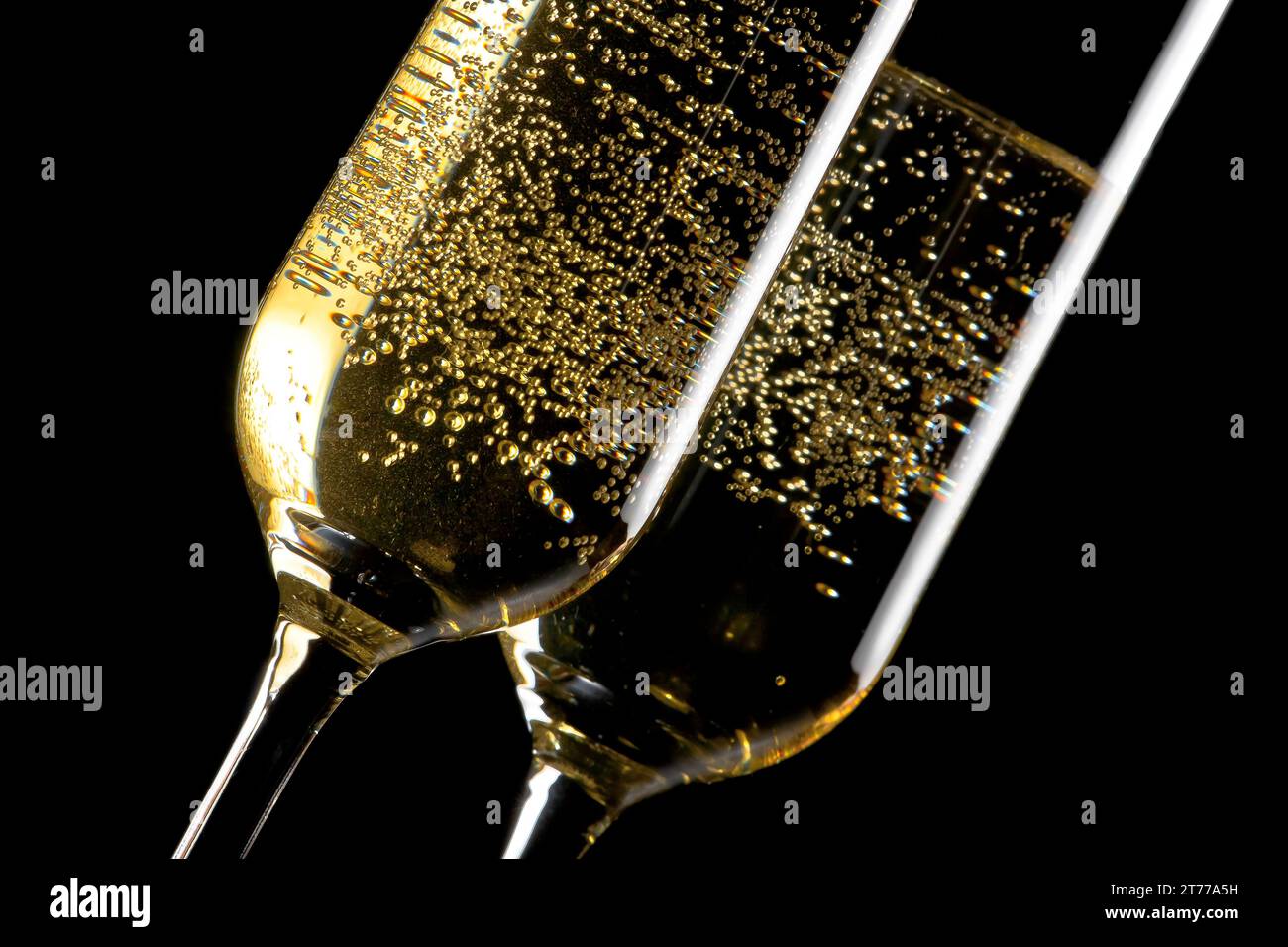 detail of a pair of flutes of champagne with golden bubbles on black