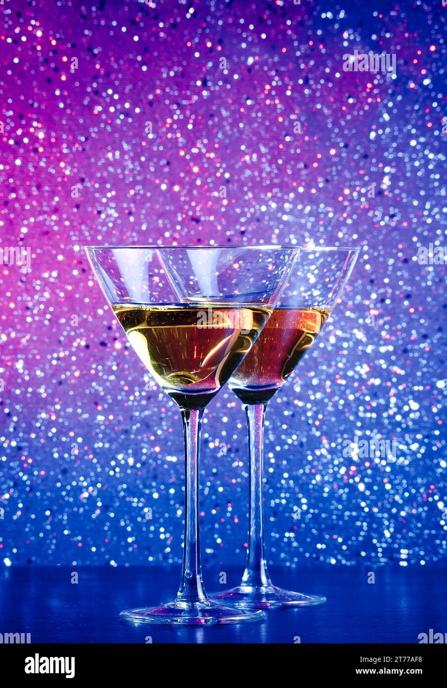 a pair of glasses of cocktail on blue and violet tint light bokeh background on bar table Stock Photo