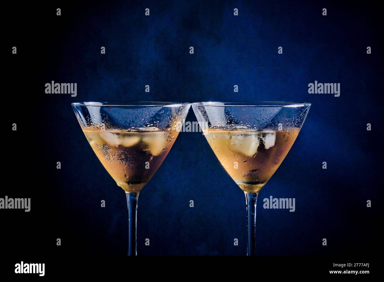 a pair of glasses of  fresh cocktail with ice on blue tint light background on bar table Stock Photo