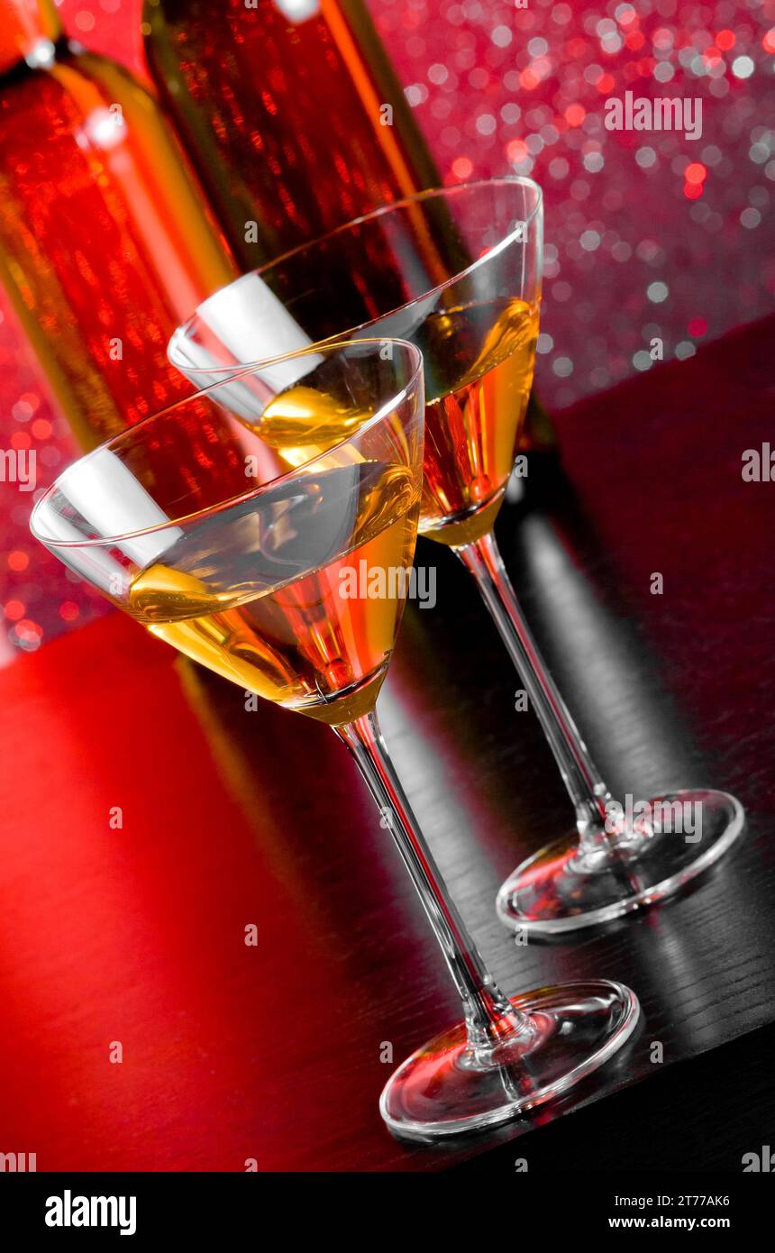 glasses of cocktail on bar table in front of bottles on red tint light bokeh background Stock Photo