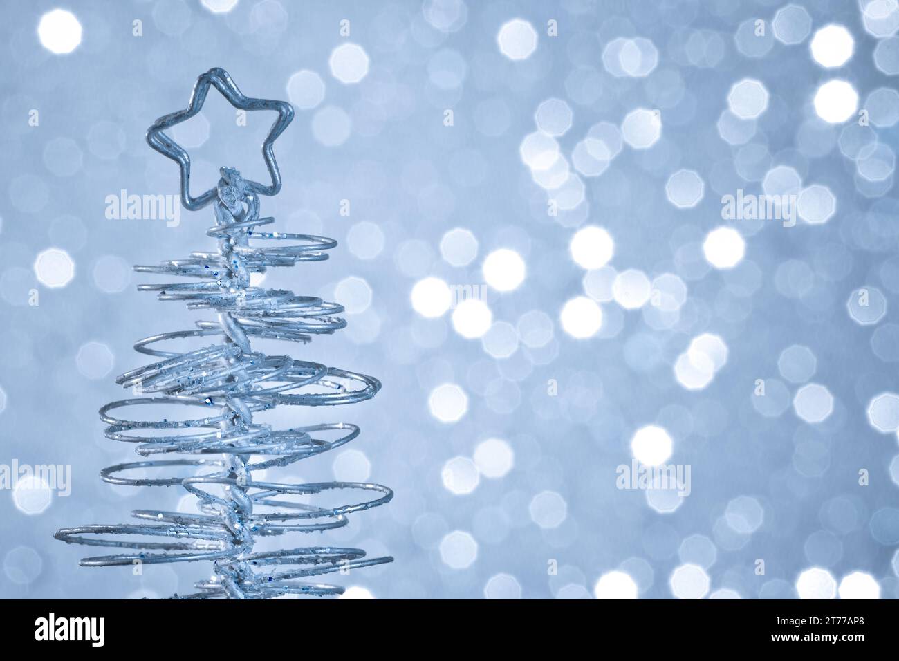detail of metallic modern christmas tree on wood table on blue tint light bokeh background with space for text Stock Photo
